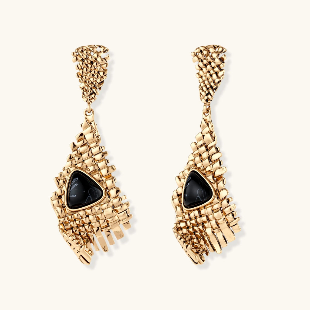 Gold-toned geometric mesh earrings with black triangular resin stones and fringe detail on neutral background