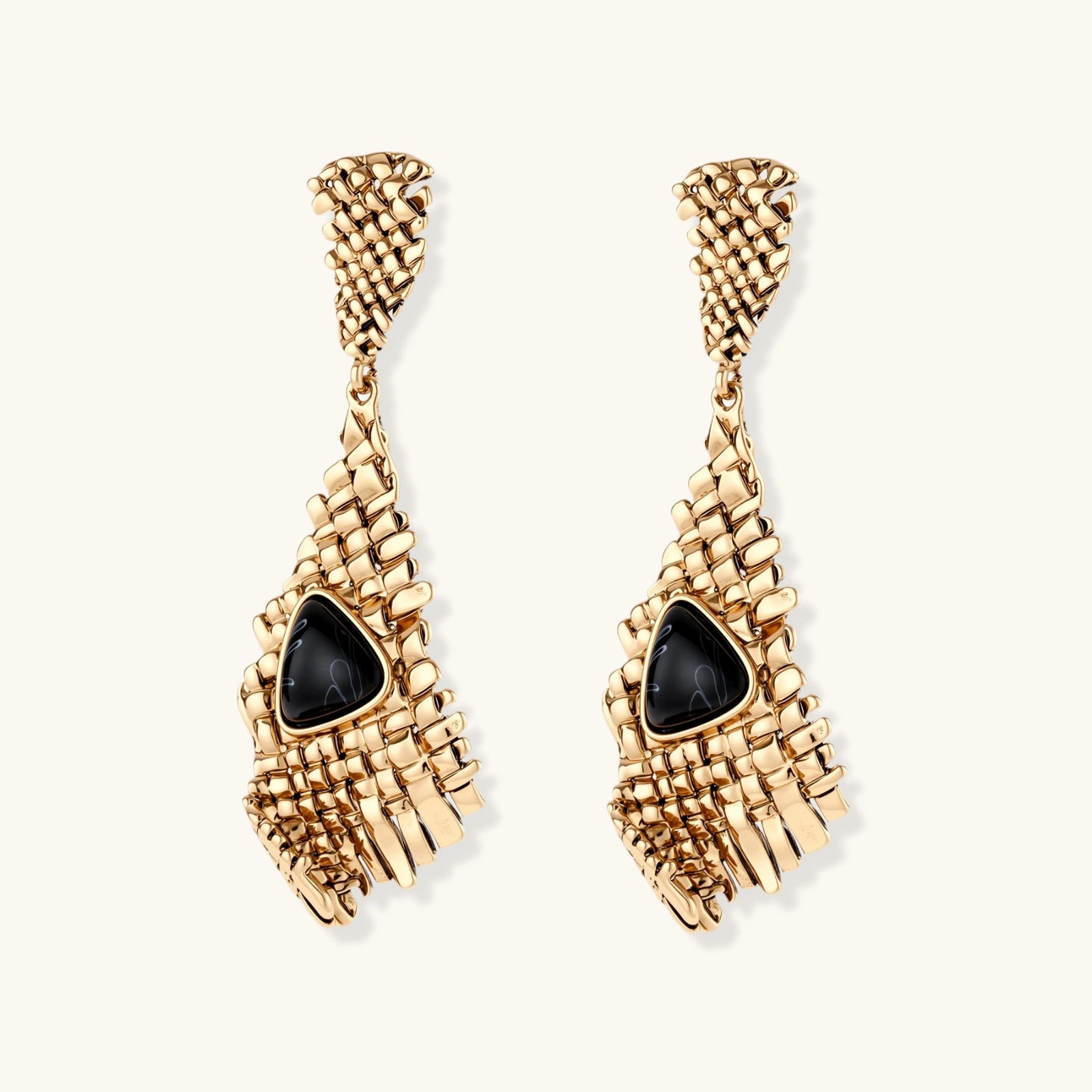Gold-toned geometric mesh earrings with black triangular resin stones and fringe detail on neutral background