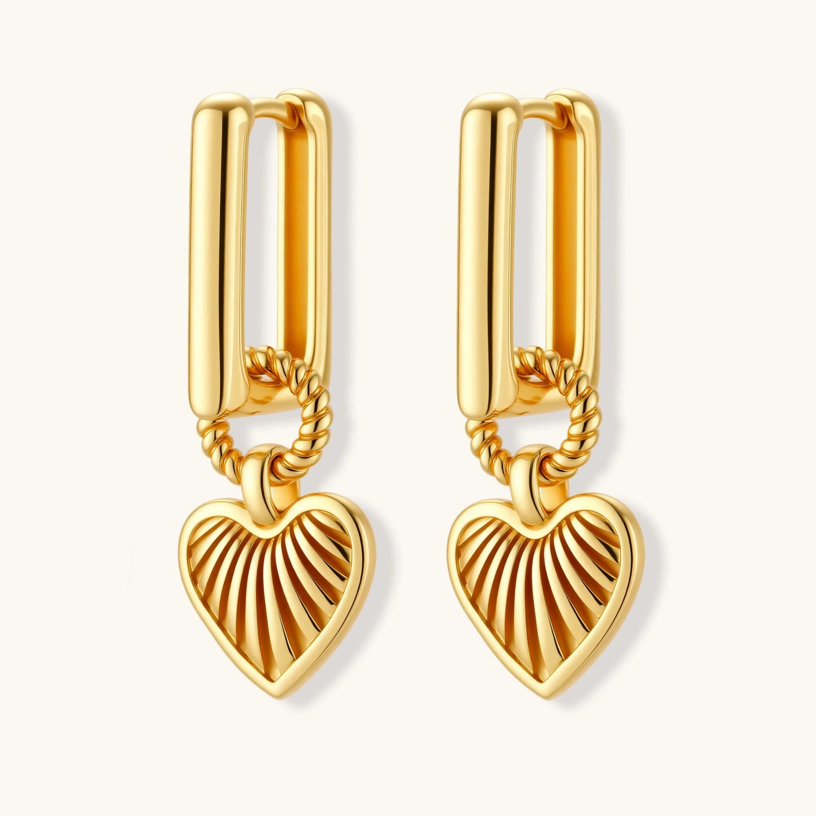 Gold-plated huggie earrings with textured heart charms featuring radiating sunburst patterns on white background.