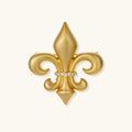 Ornate gold-plated fleur-de-lis brooch with crystal band detail on white background, showing brushed metal finish.