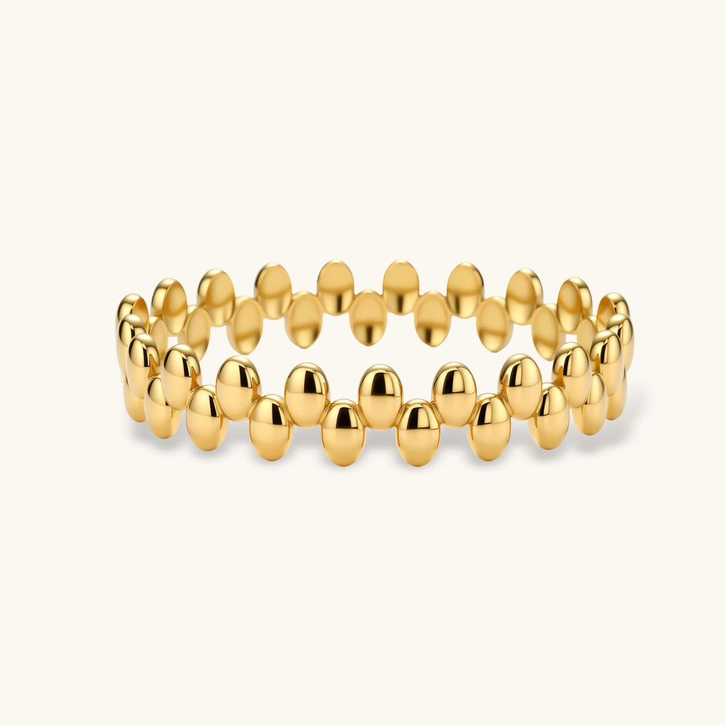 18K gold plated stainless steel bangle with dual rows of polished oval pebble beads on a cream background.