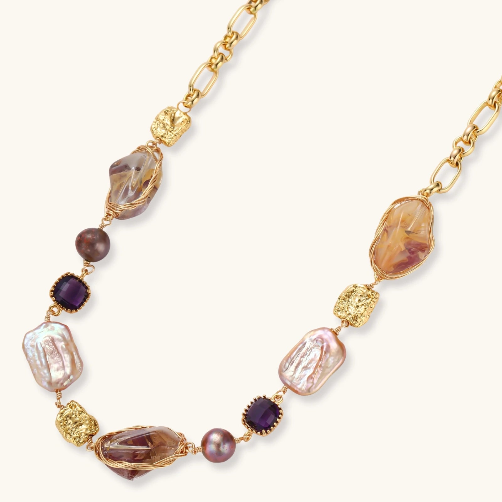 Gold-plated necklace with baroque pearls, purple amethyst stones, and wire-wrapped details on white background.
