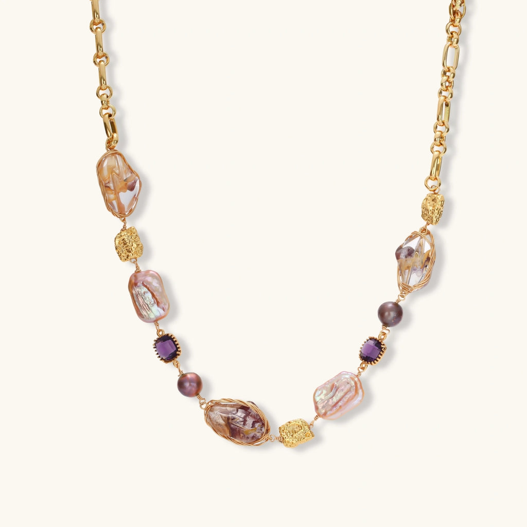 Gold-plated necklace with baroque pearls, purple amethyst stones, and wire-wrapped details on white background.