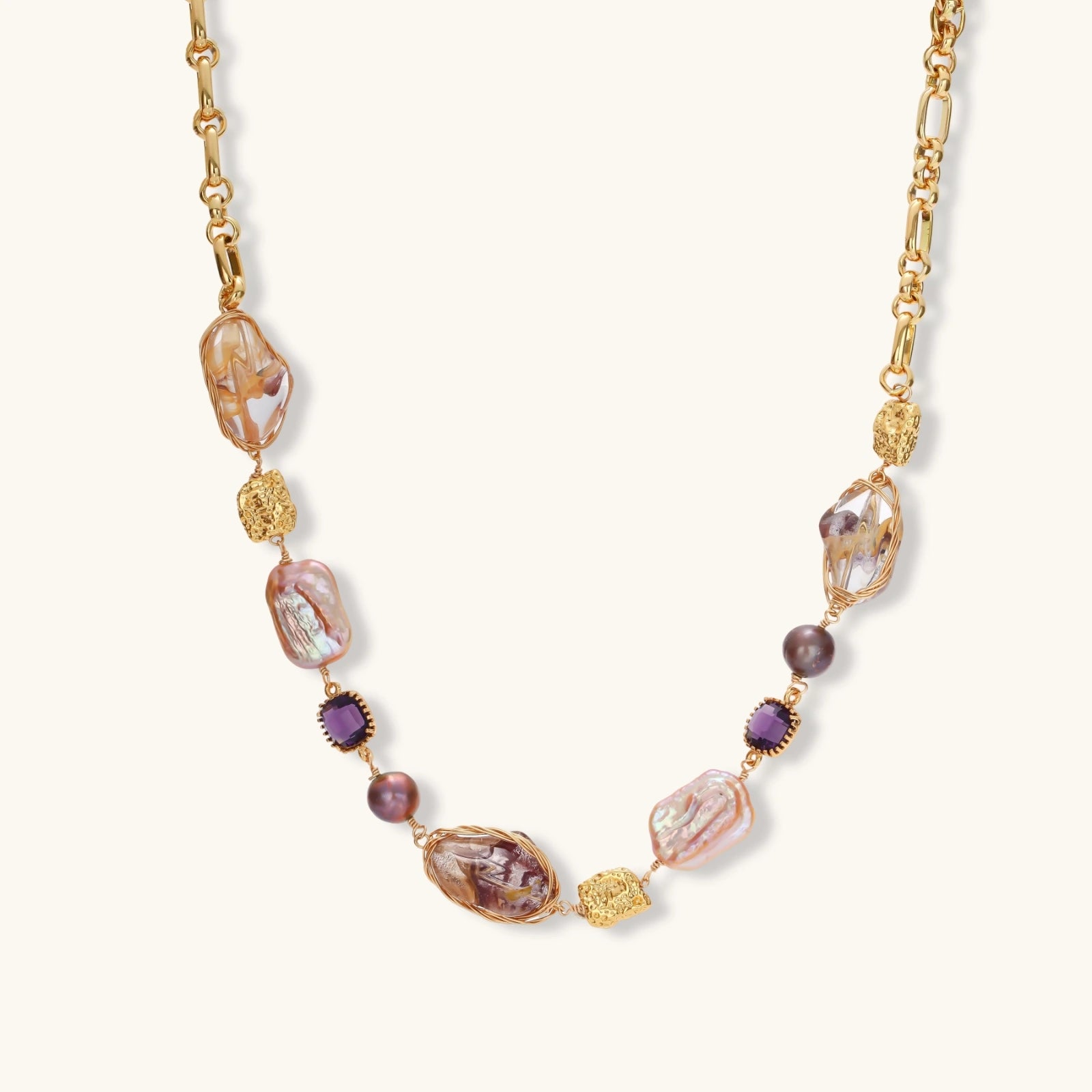 Gold-plated necklace with baroque pearls, purple amethyst stones, and wire-wrapped details on white background.